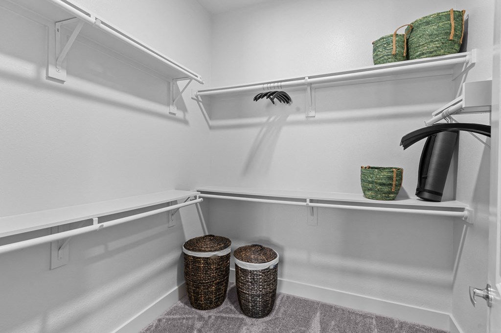 a walk in closet with white walls and shelves and wicker baskets