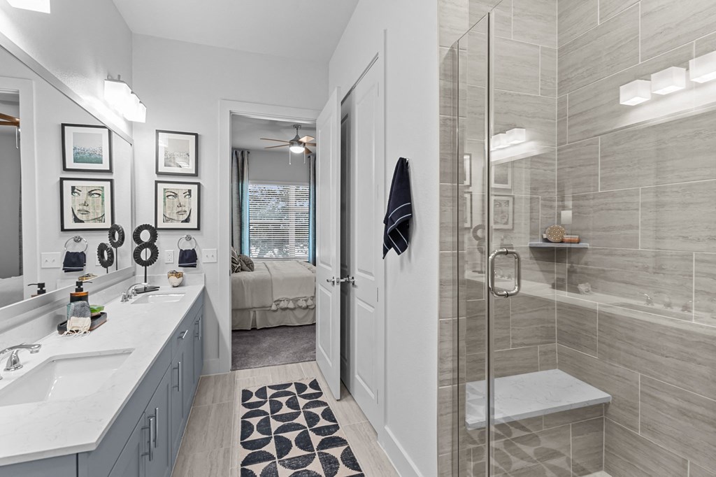 a bathroom with a shower and a sink and a bed