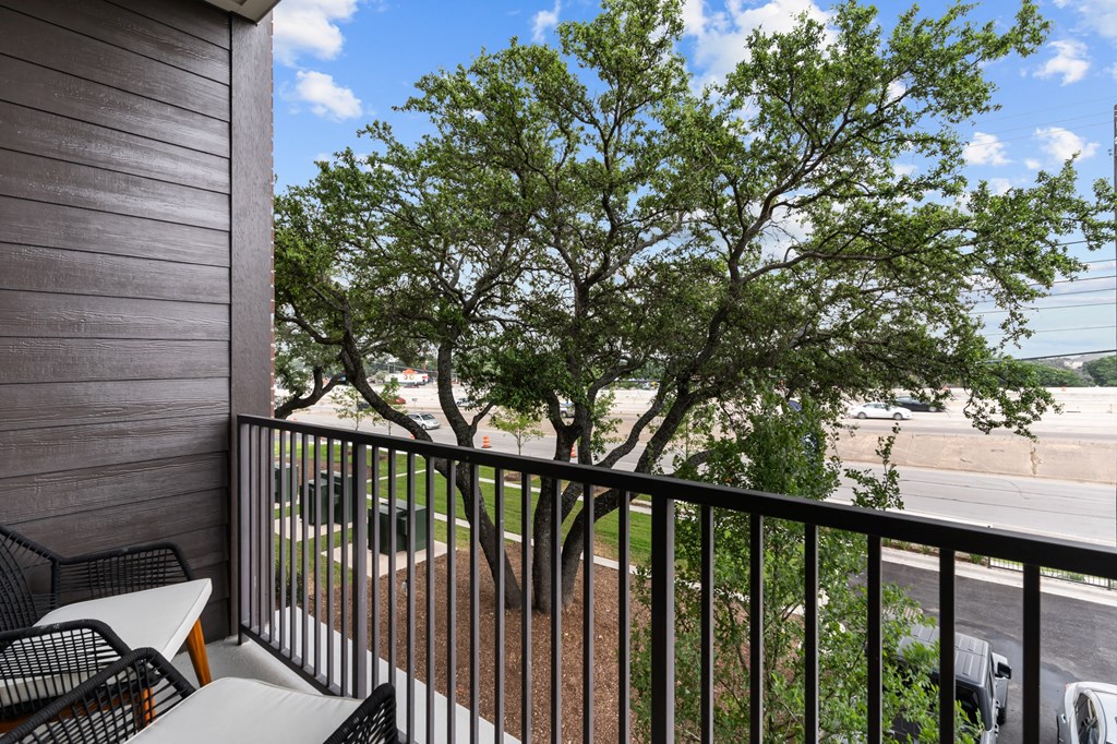 a balcony with a tree and tables and chairs