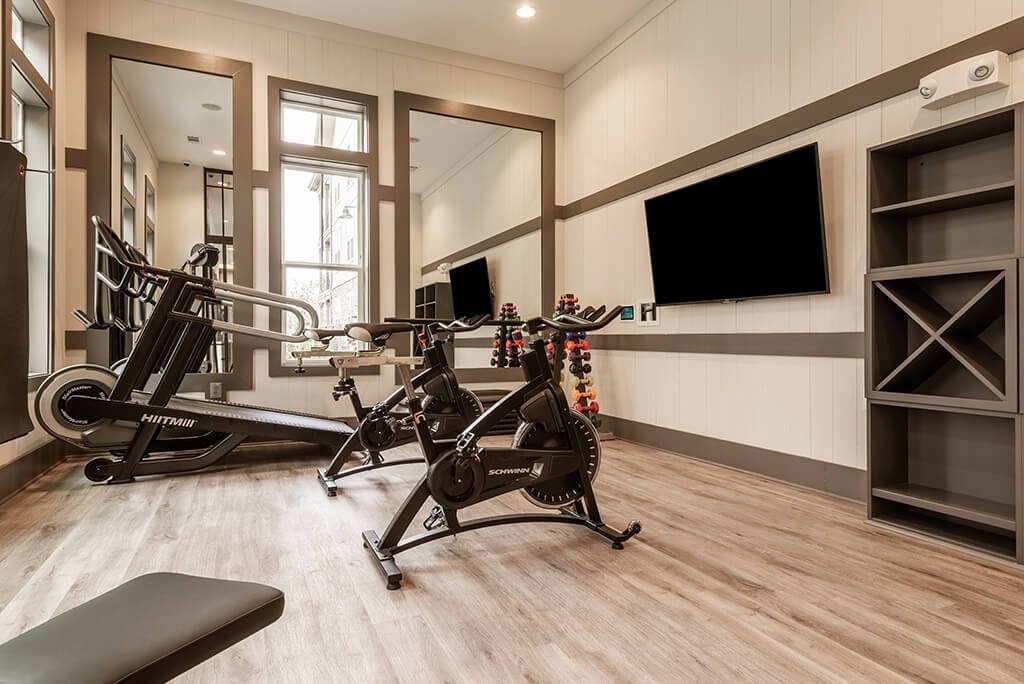 A home gym with a variety of equipment including a treadmill, stationary bike, and weight machines.