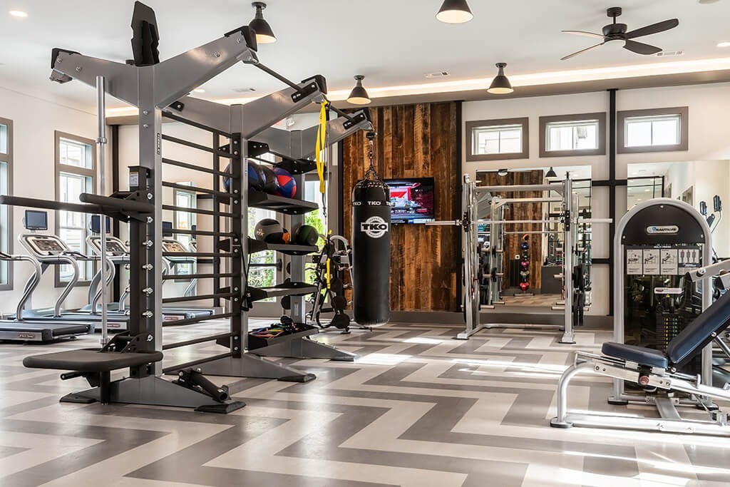 A gym with a variety of equipment including a treadmill, weights, and a bench press.