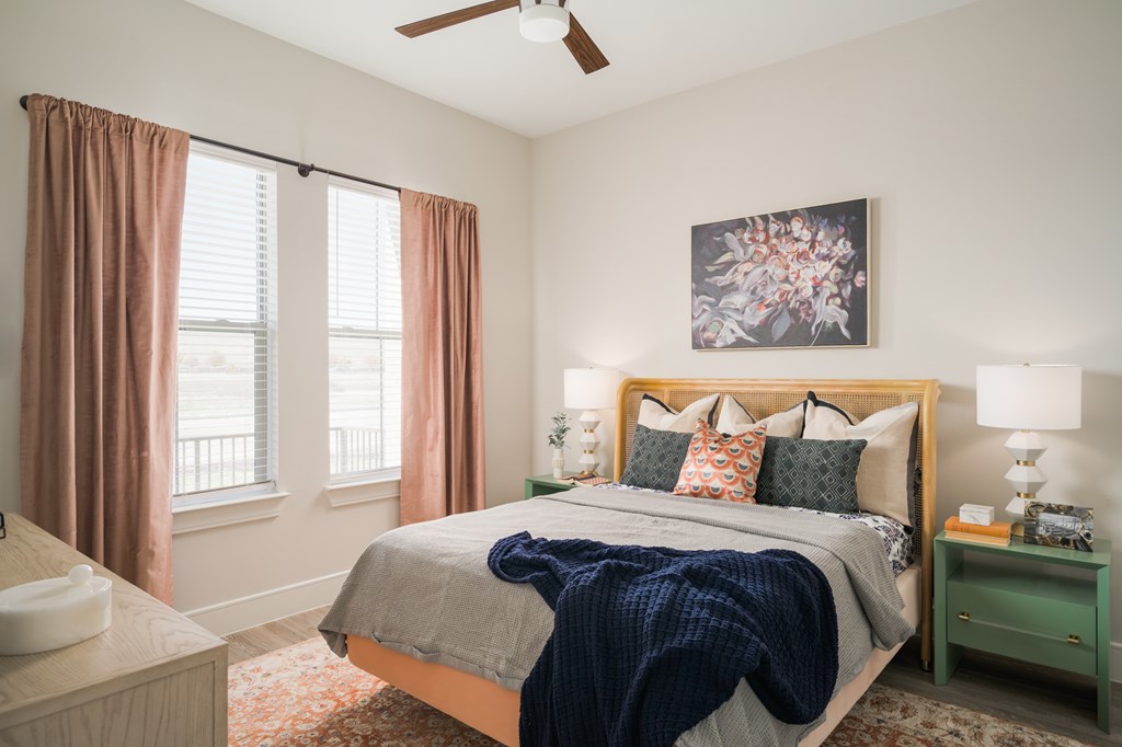 A bedroom with a bed, nightstand, and window with curtains.