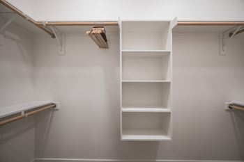 A white shelving unit with four shelves is mounted on a white wall.
