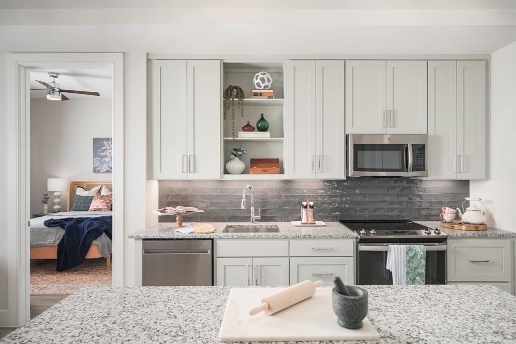 A kitchen with a bed in the foreground.