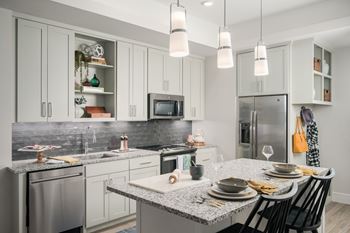 A modern kitchen with a granite countertop and stainless steel appliances.