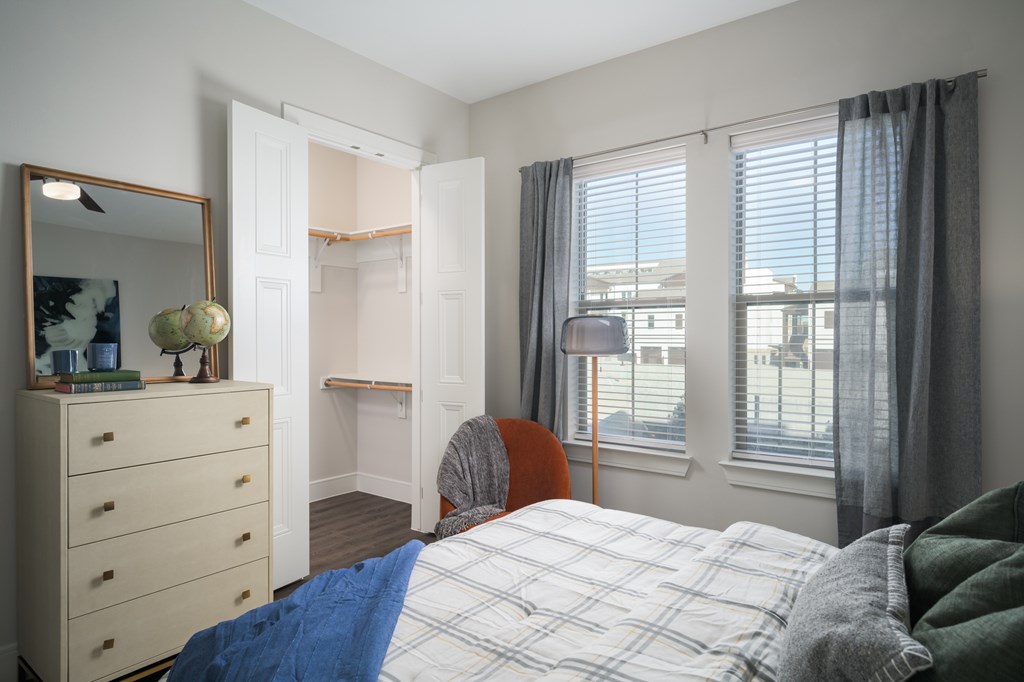 A bedroom with a bed, dresser, and window.