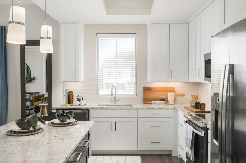 A kitchen with white cabinets and a marble countertop.