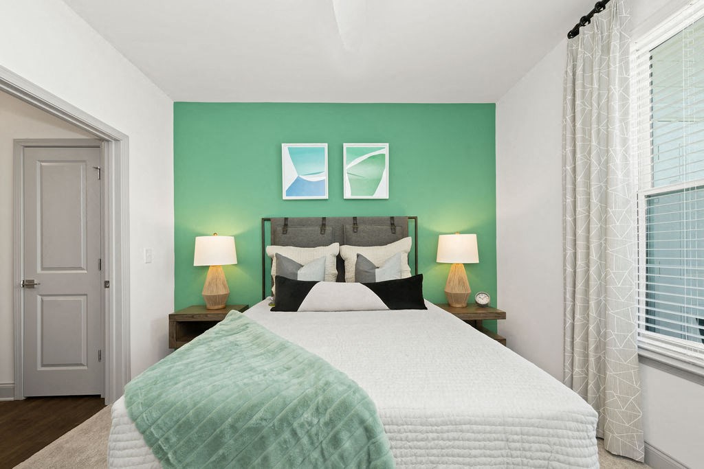 a bedroom with a large bed and two windows