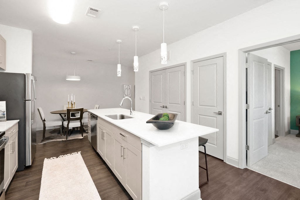 a kitchen with white cabinetry and a large white island with a sink