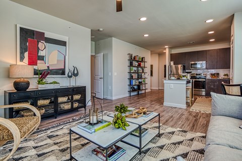 A modern living room with a black and white rug, a glass coffee table, and a painting on the wall.