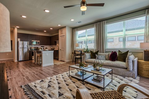 A modern living room with a kitchen area in the background.