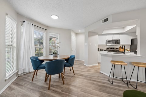 A kitchen with a dining table and chairs.