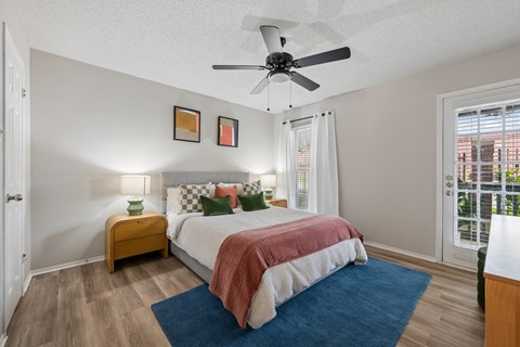 A bedroom with a bed, a ceiling fan, and a window with blinds.