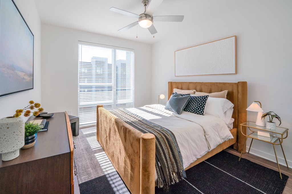 A bedroom with a bed, nightstand, and a ceiling fan.