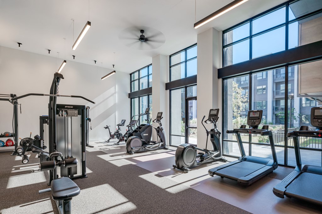 A gym with a variety of equipment including treadmills, weights, and exercise machines.