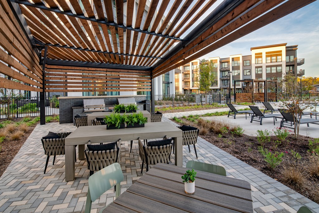 A patio with a table and chairs under a wooden pergola.