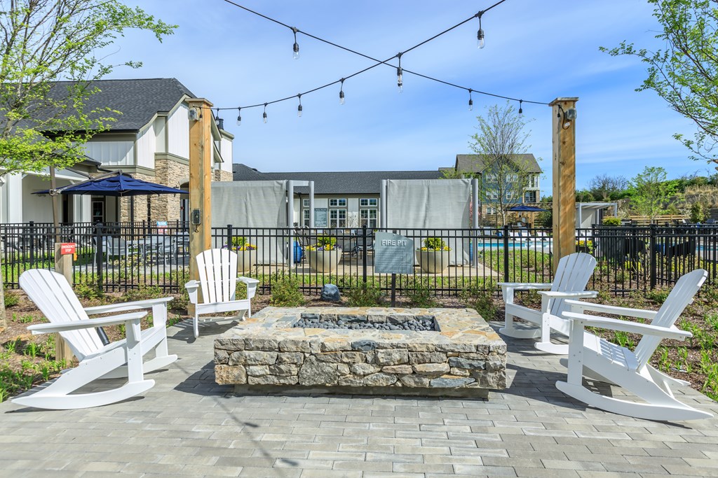 A patio with white chairs and a fire pit.