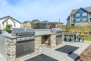 A stone outdoor kitchen with a grill and sink.