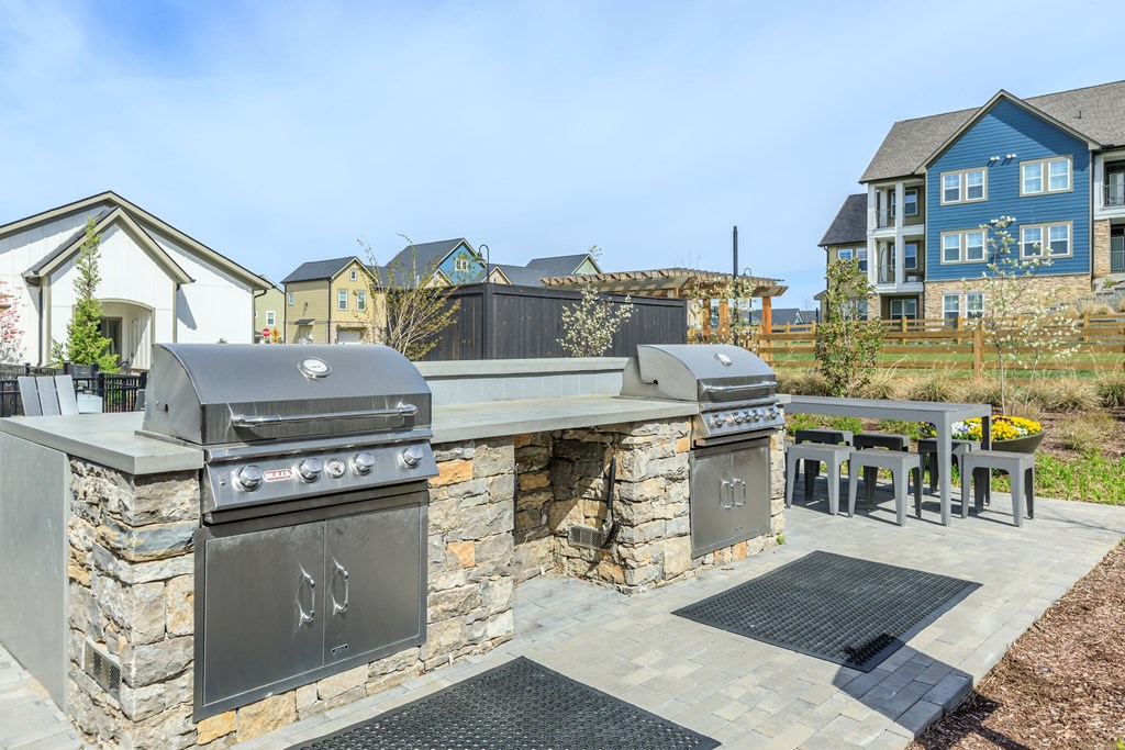A stone outdoor kitchen with a grill and sink.