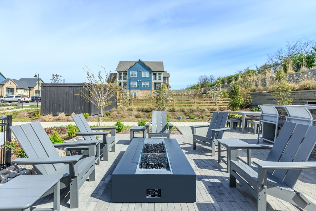A modern outdoor seating area with a fire pit and chairs.