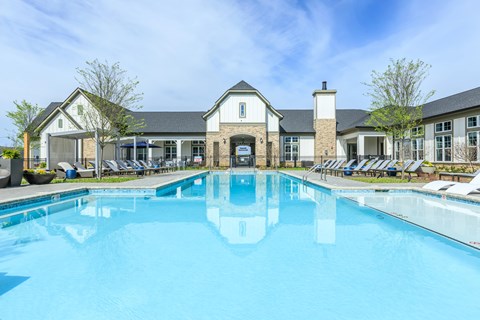 A large swimming pool in front of a building with a white facade.