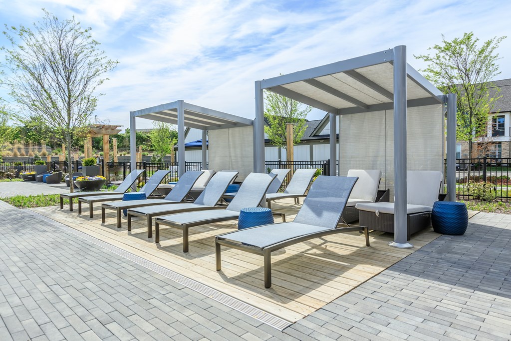 A row of blue and white lounge chairs are arranged on a patio.