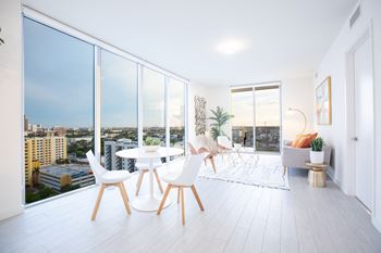 a living room with a table and chairs and a large window with a view of the city