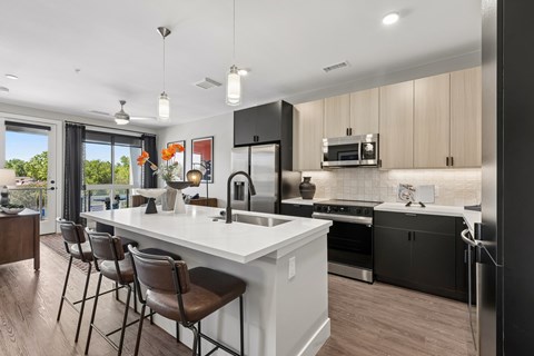 A modern kitchen with a white island and dark wood floors.