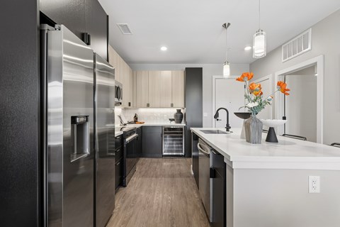 A modern kitchen with a stainless steel refrigerator and wooden flooring.