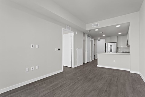 A spacious room with wooden flooring and white walls.
