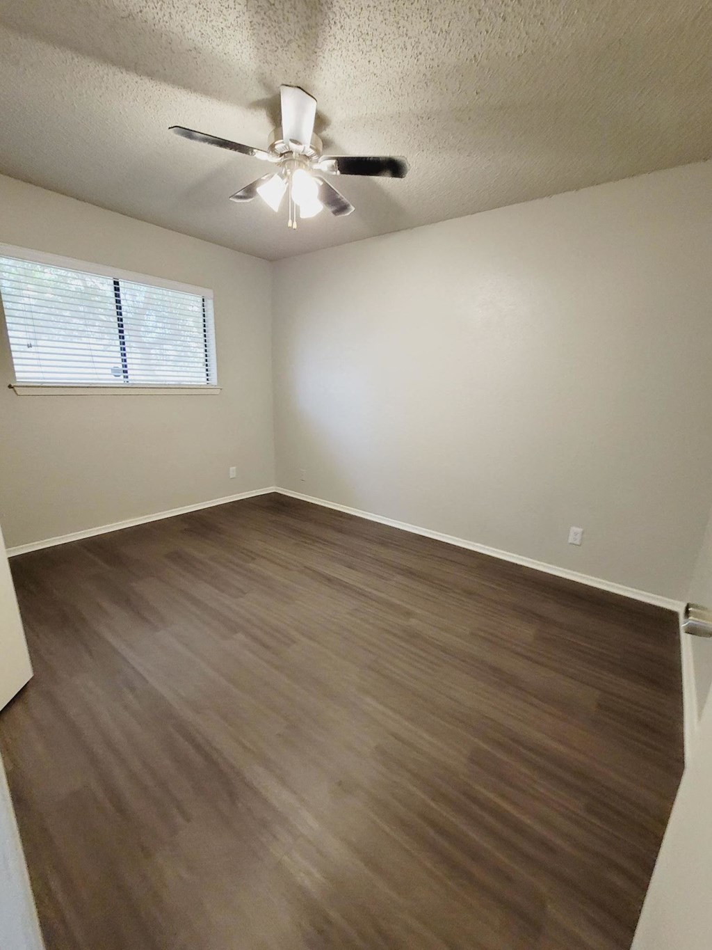 an empty living room with wooden floors and a ceiling fan