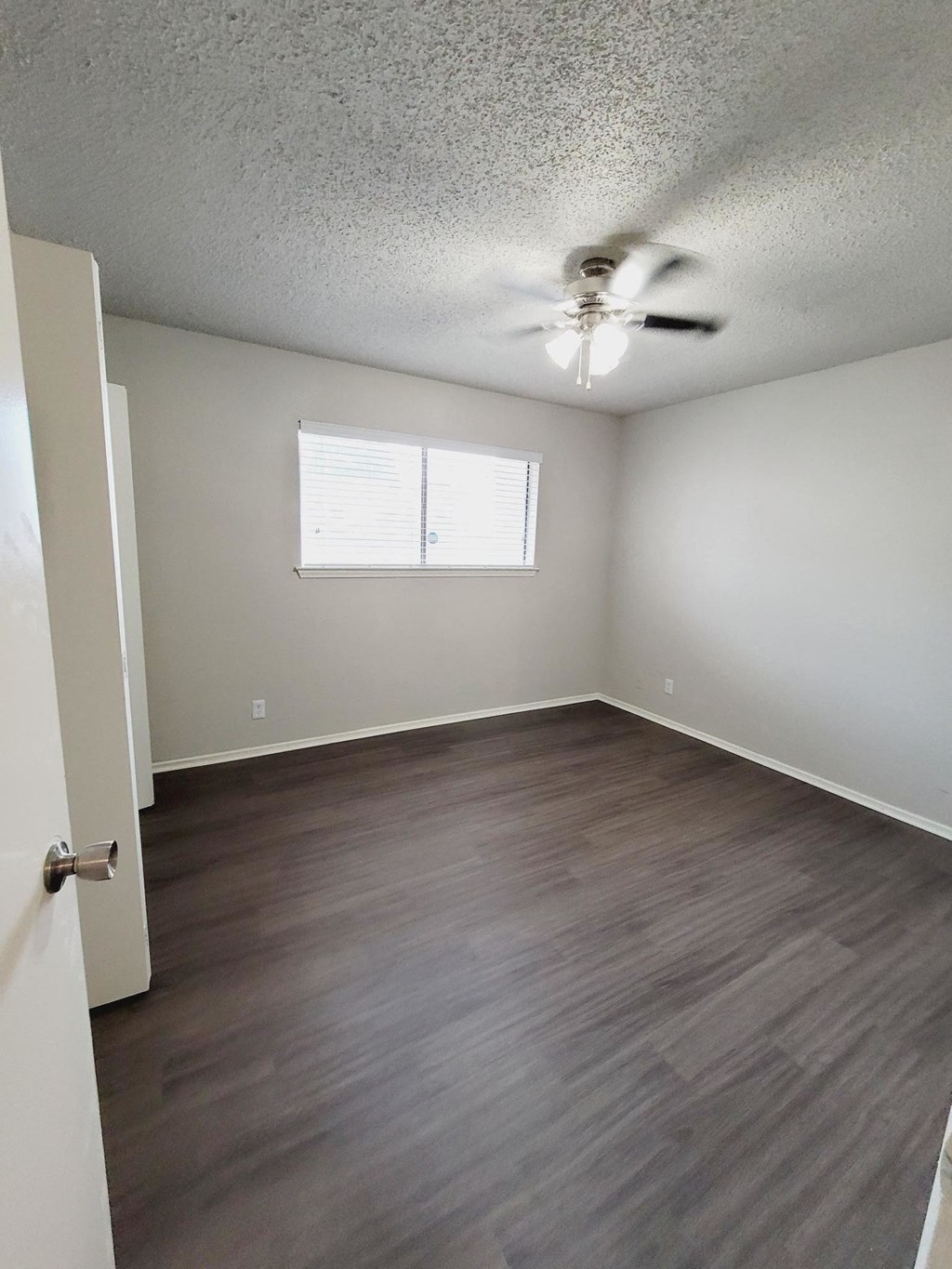 an empty living room with wood floors and a ceiling fan