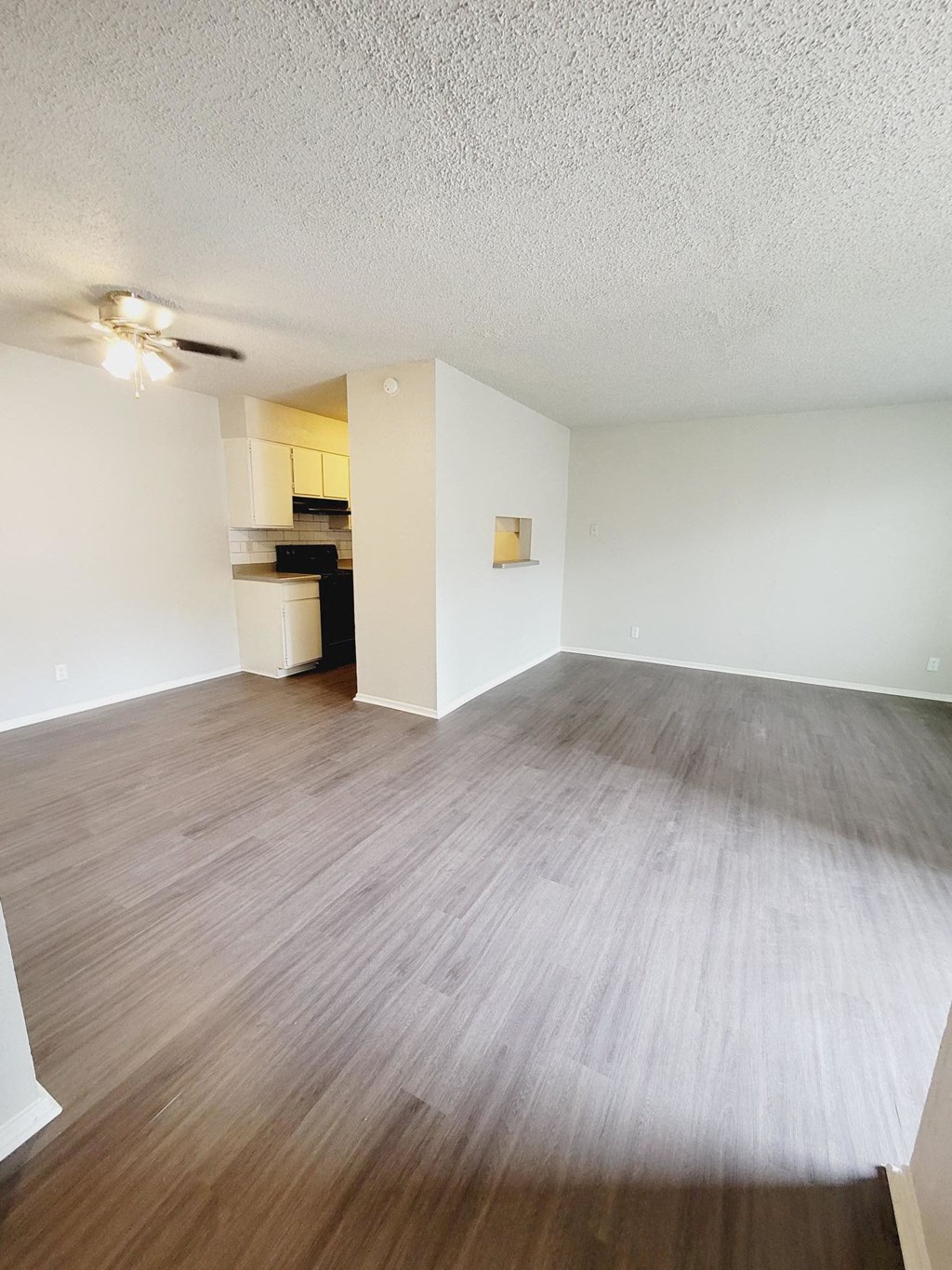 an empty living room with a wood floor and a ceiling fan