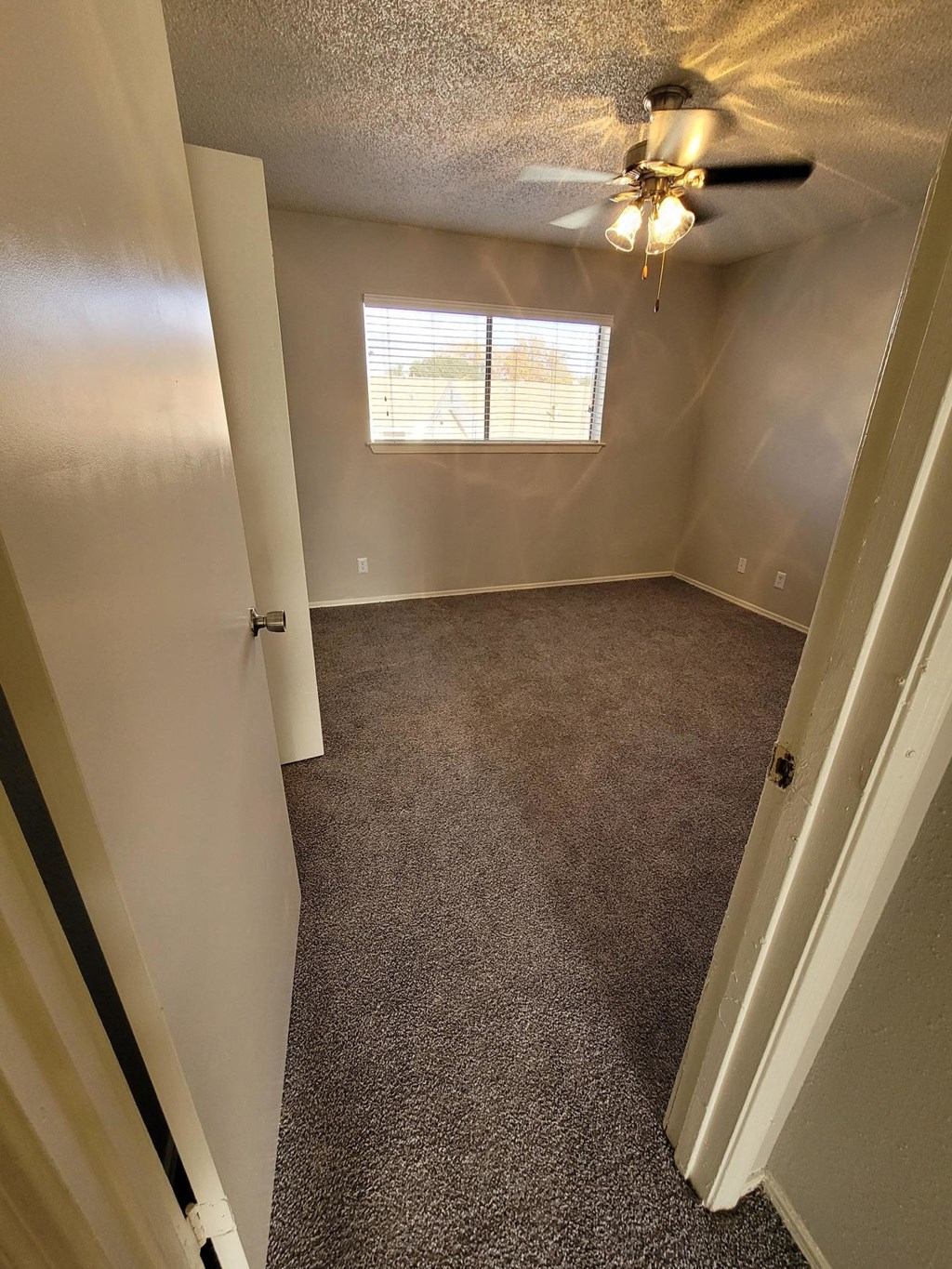 an empty room with a ceiling fan and a window