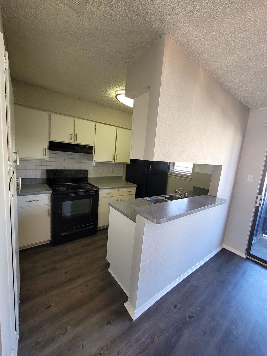 an empty kitchen with white cabinets and black appliances