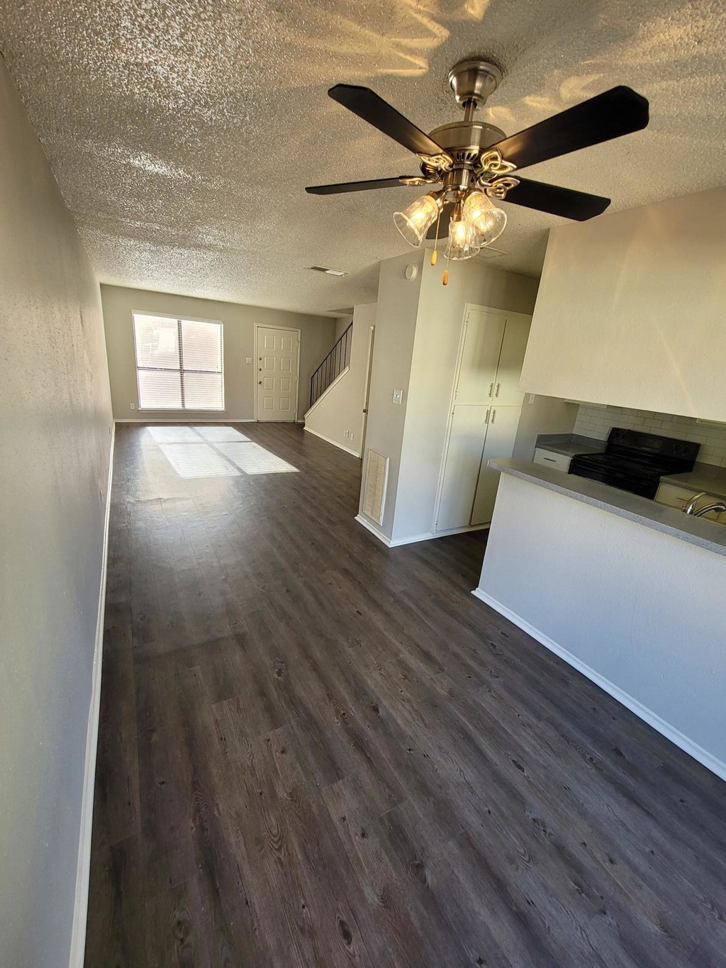 a empty living room with a ceiling fan and wood floors