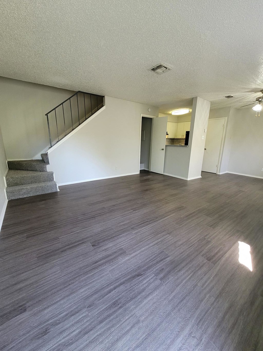 an empty living room with wood flooring and a staircase