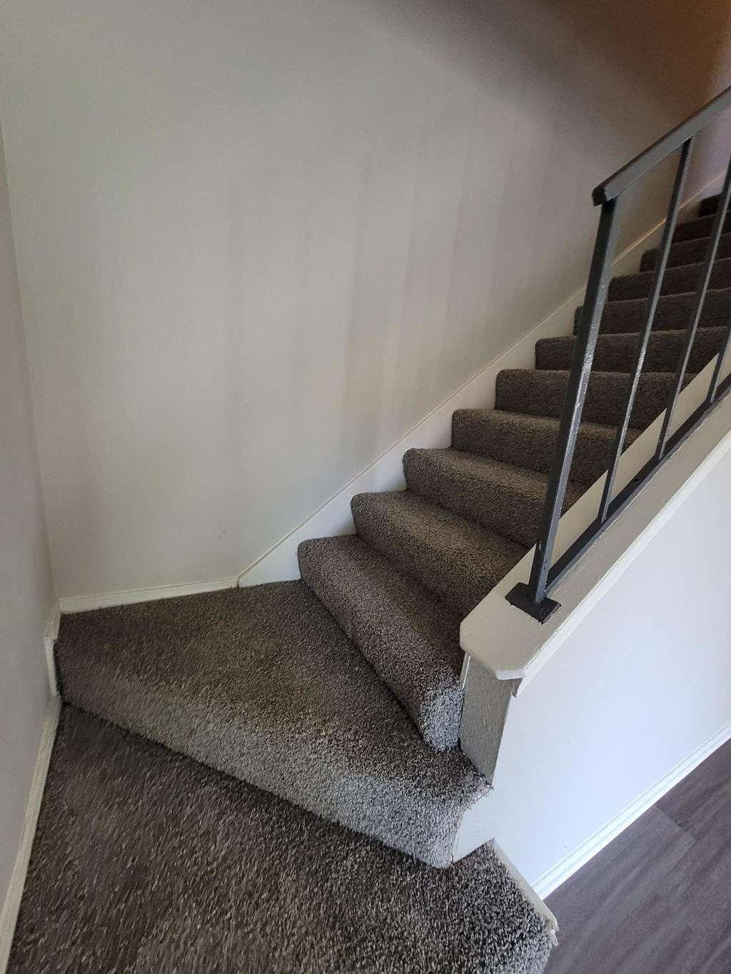 a carpeted staircase with white walls and brown carpeted stairs
