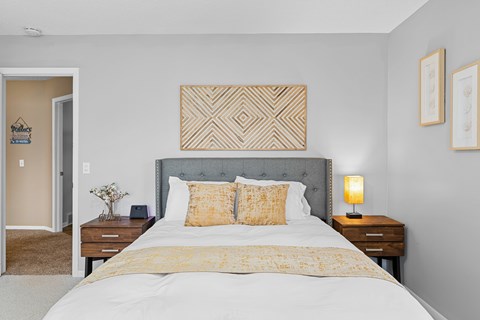 A bedroom with a large bed and a grey headboard.