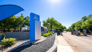 A blue sign with a white arrow pointing upwards is on the left side of a paved road.