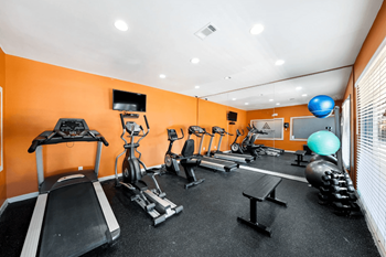 A gym with orange walls and a variety of exercise equipment.