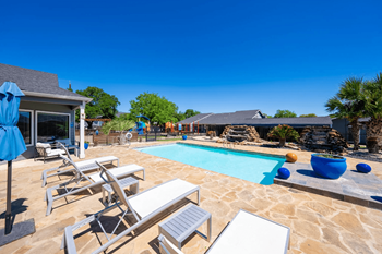 A pool with a bench and chairs around it.