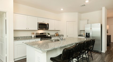 A kitchen with white cabinets and a granite countertop.