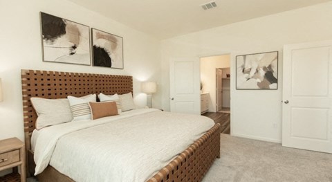A bedroom with a large bed and two framed pictures on the wall.