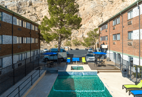 the pool is next to a building with a mountain in the background