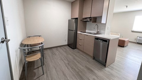 a small kitchen with a counter and a bar stool and a refrigerator