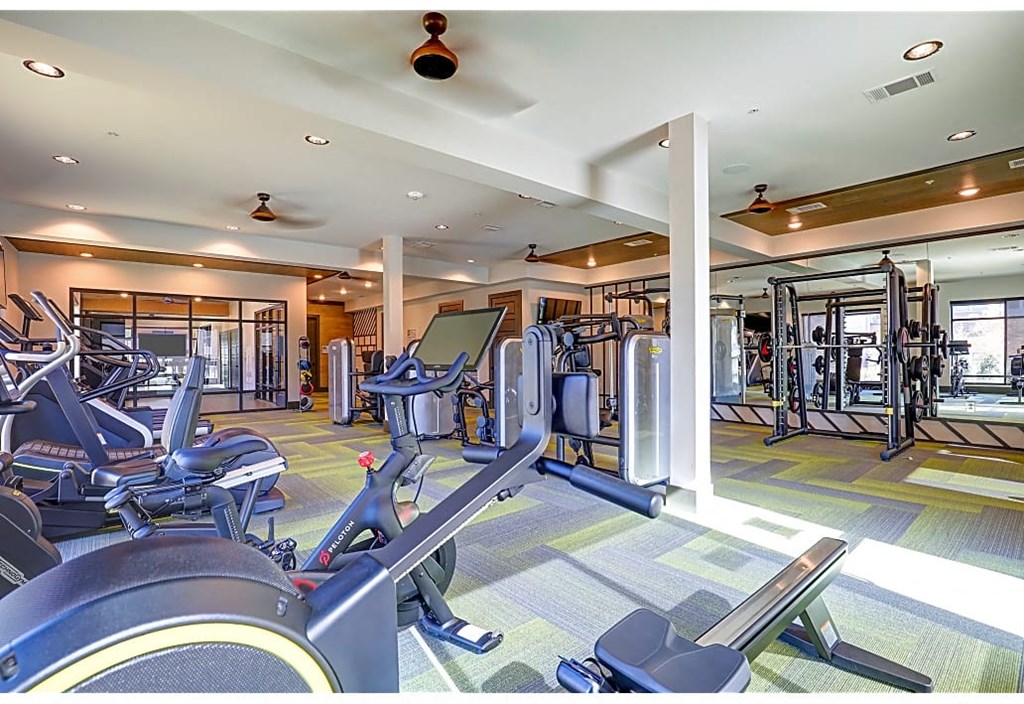 A gym with a variety of equipment including treadmills, weights, and exercise machines.