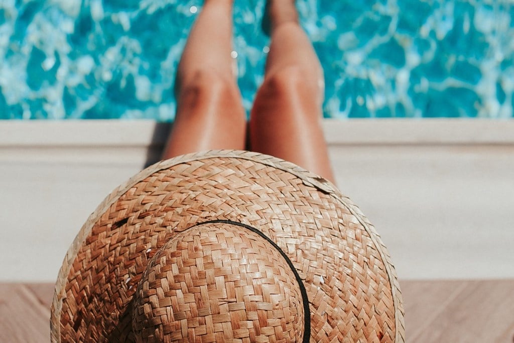 a woman with her feet up on a straw ball by a pool