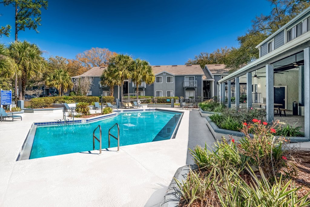 A swimming pool surrounded by a concrete floor and a building with a glass door.