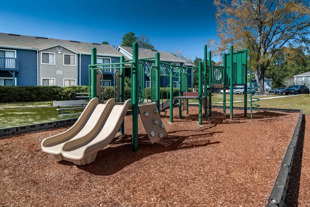 A playground with a green swing set and a slide.